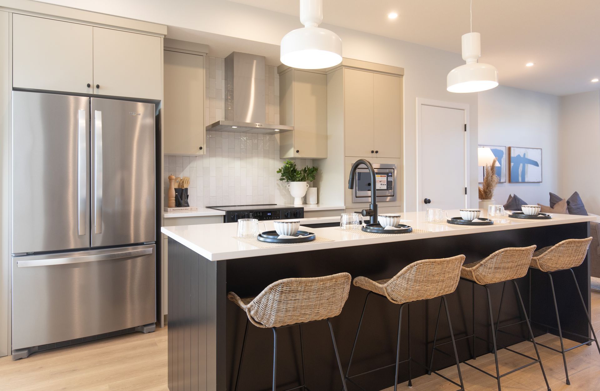 A kitchen with stainless steel appliances and a large island with wicker chairs.