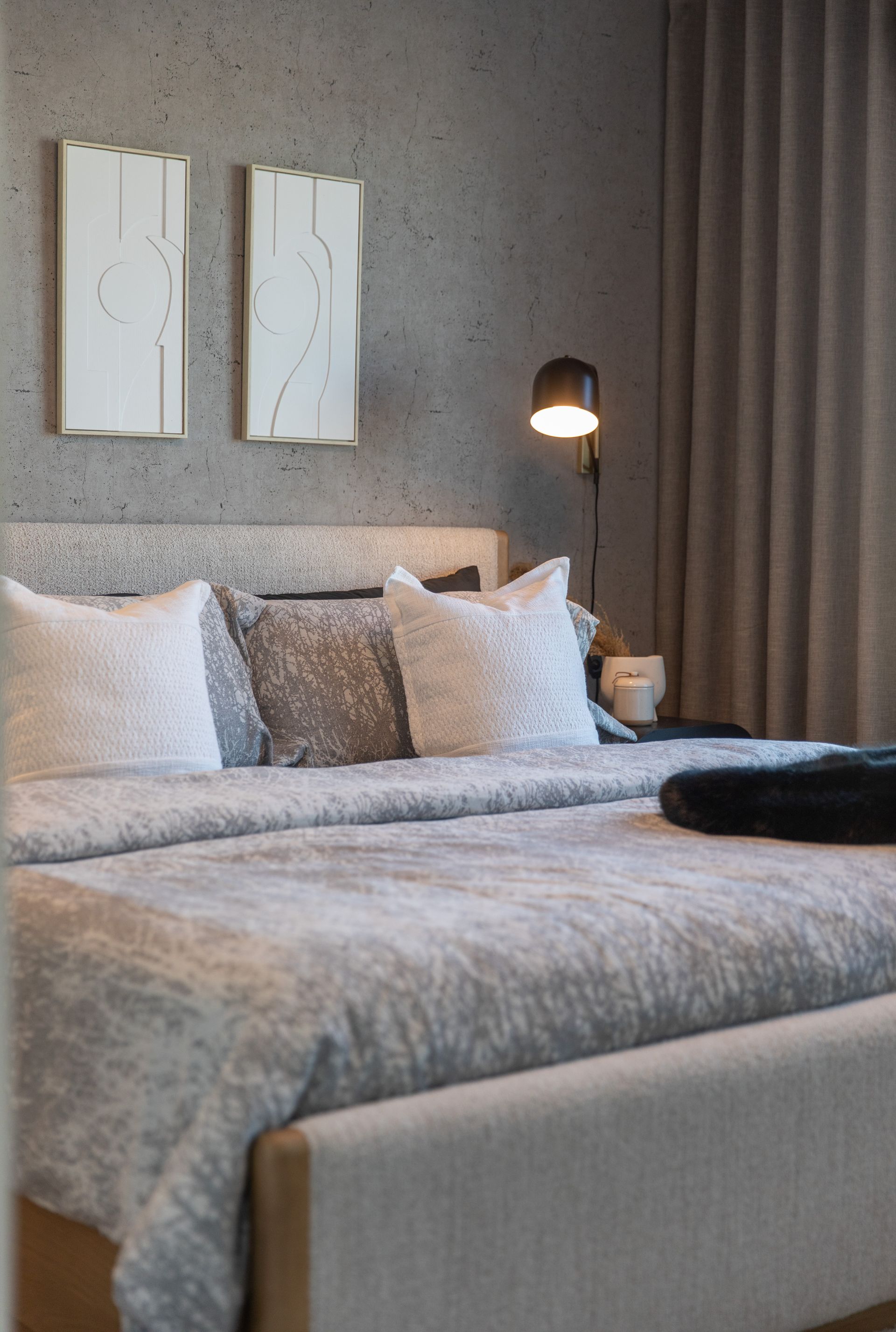 A bedroom with a bed , lamp , and two paintings on the wall.