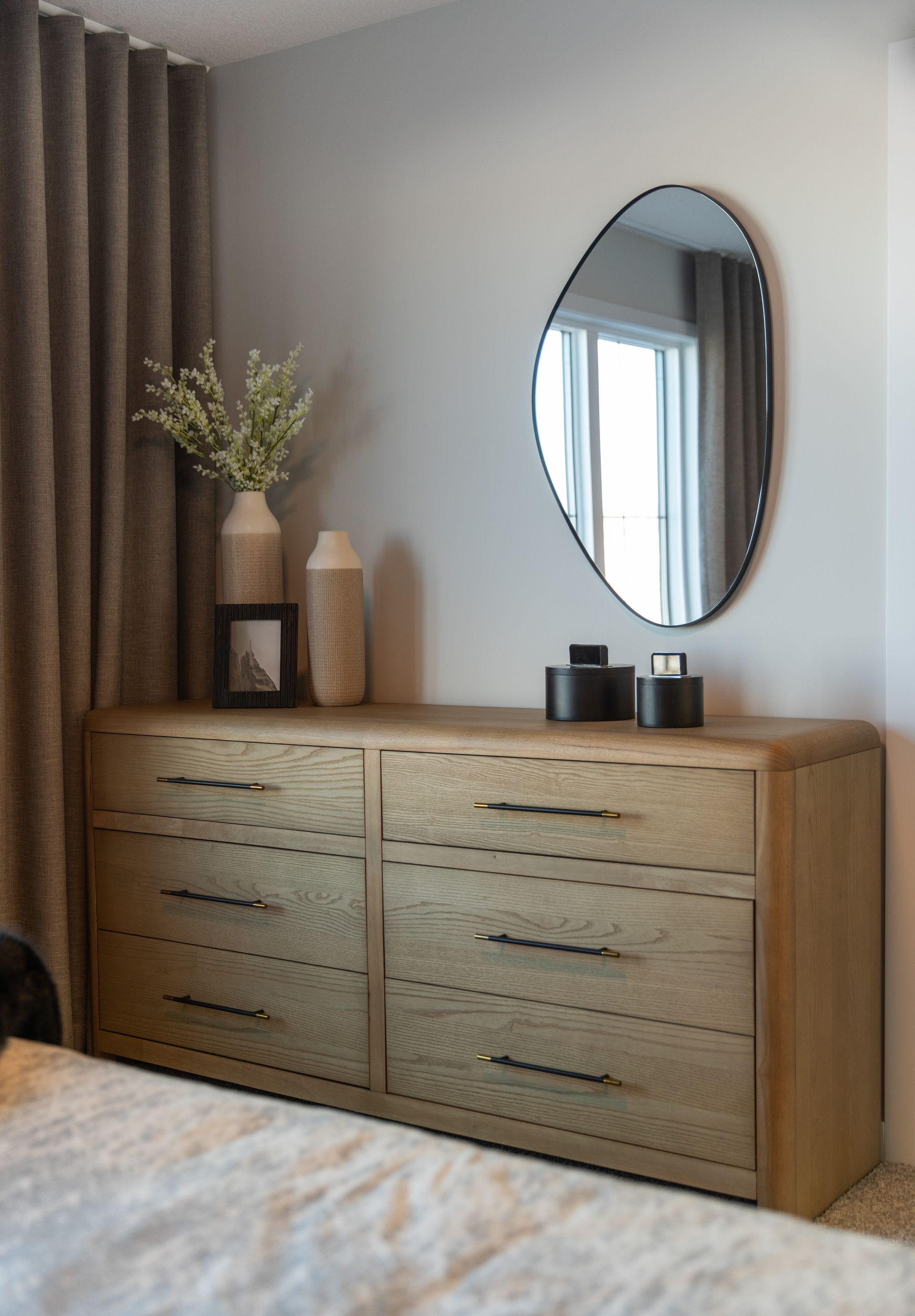 A bedroom with a dresser and a mirror on the wall