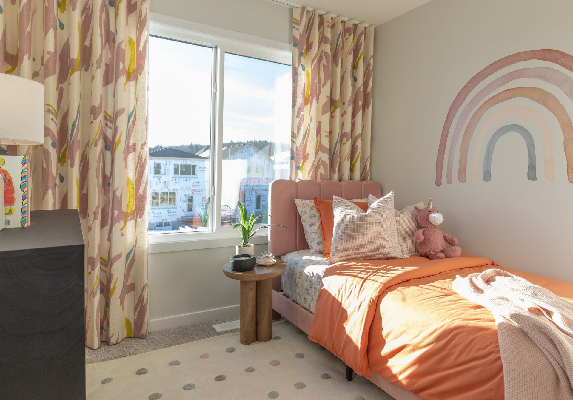 A bedroom with a bed and a rainbow on the wall.