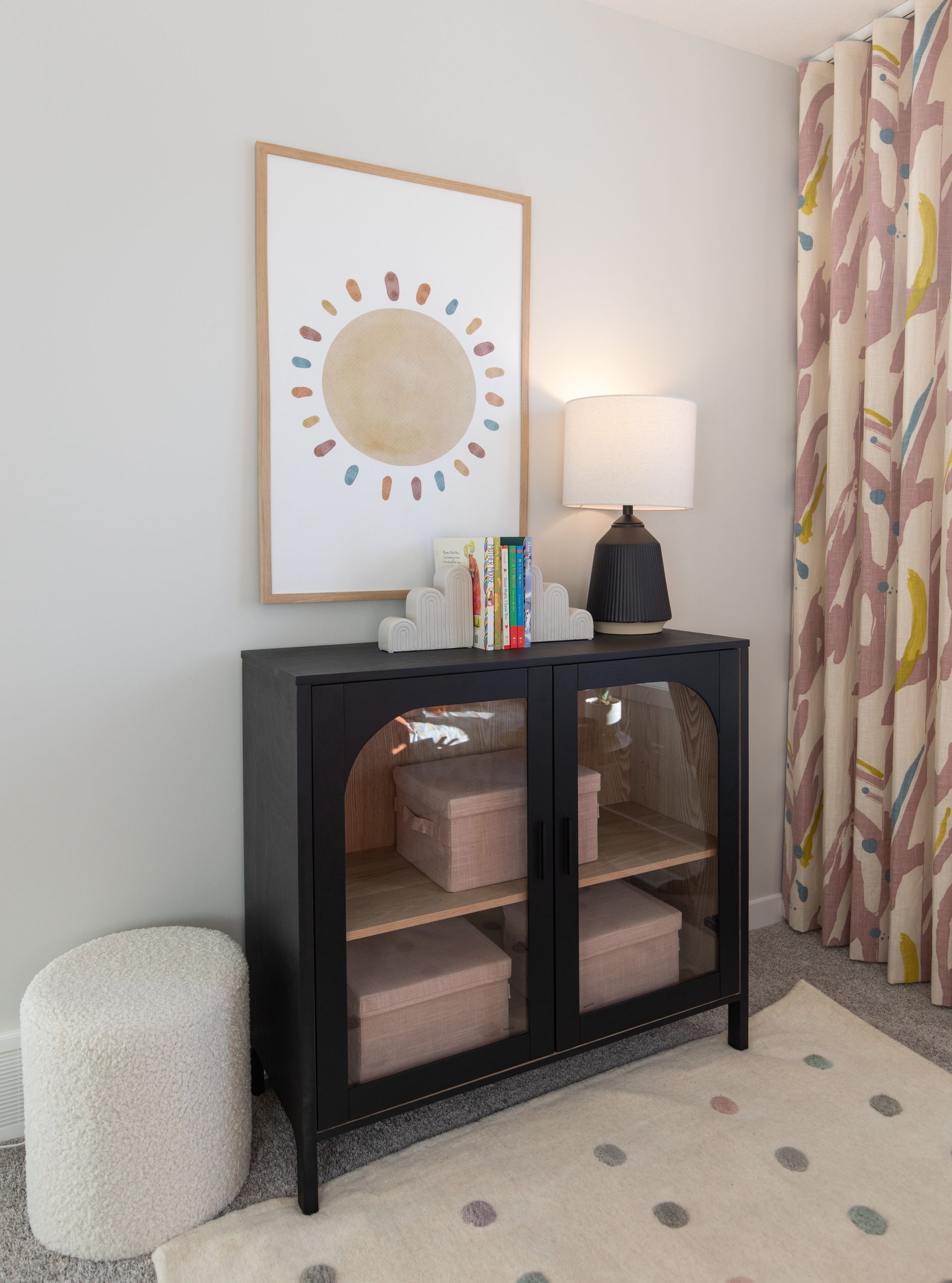 There is a picture of a sun on the wall above a dresser.