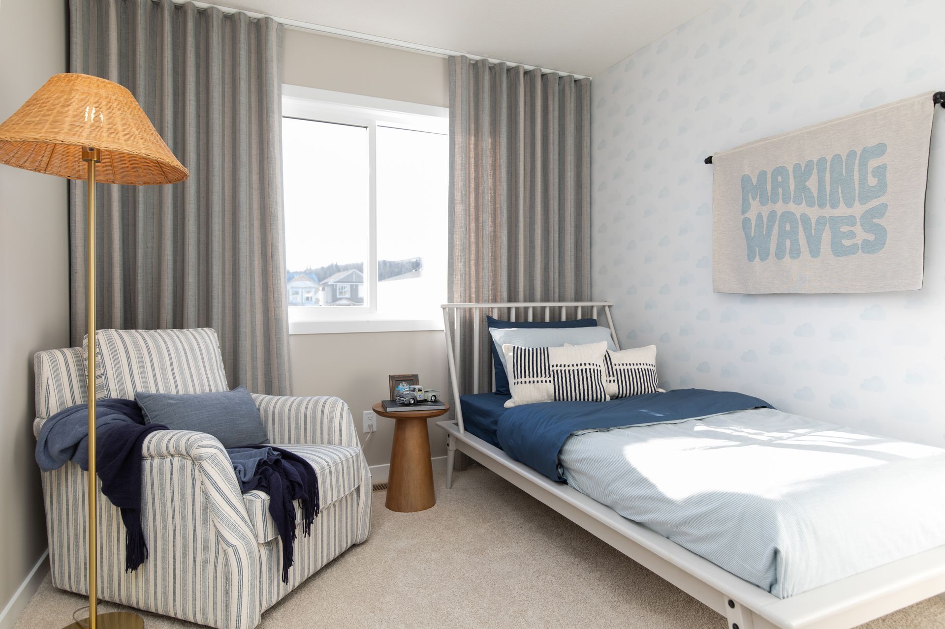 A bedroom with a bed , chair , lamp and a sign on the wall that says `` making waves ''.