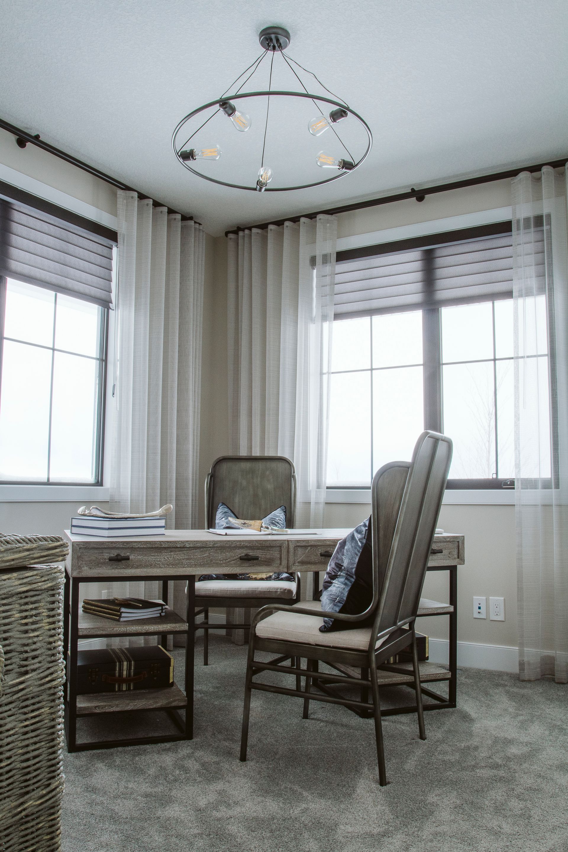A home office with a desk , chairs , and a chandelier.