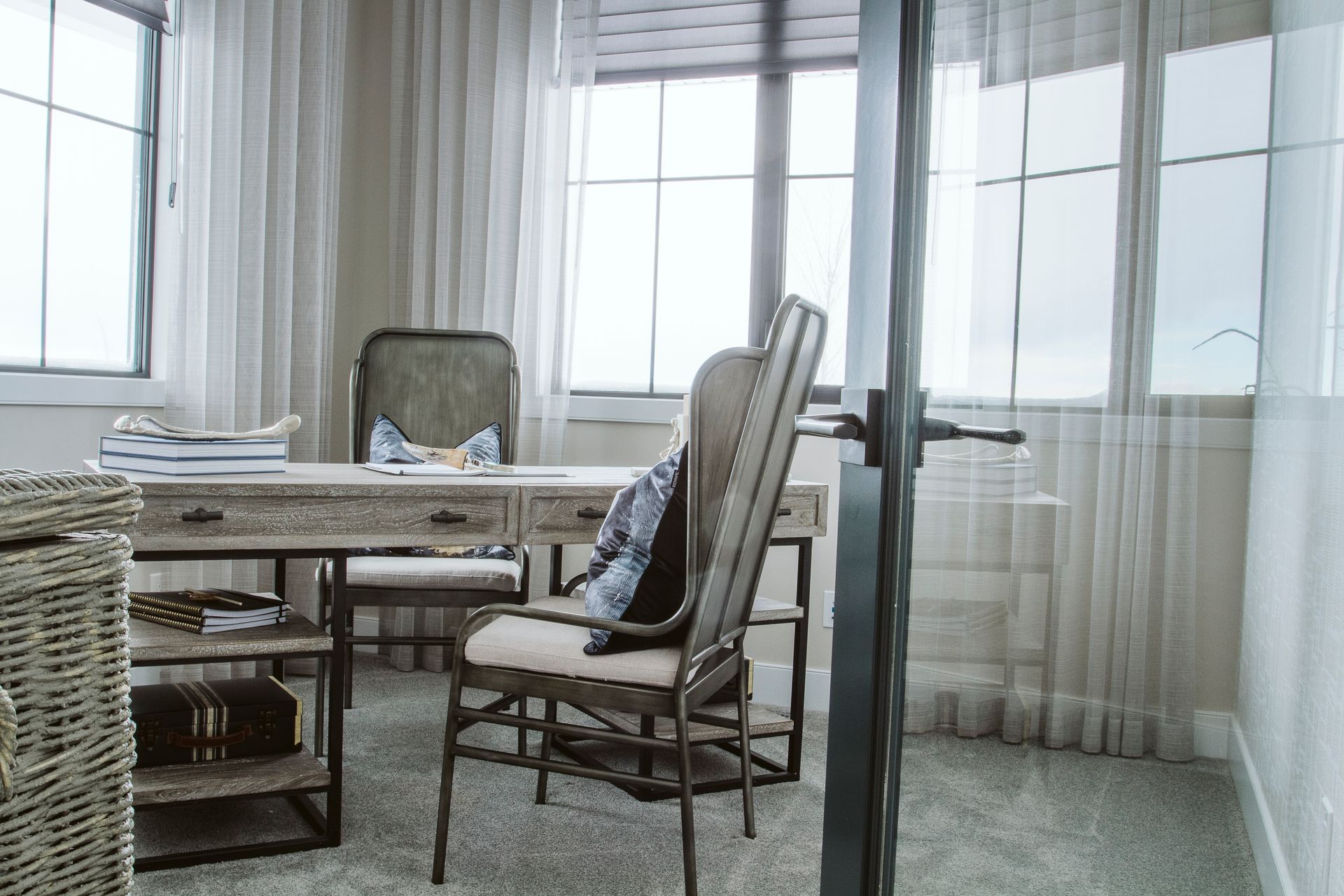A home office with a desk and chairs and a glass door.