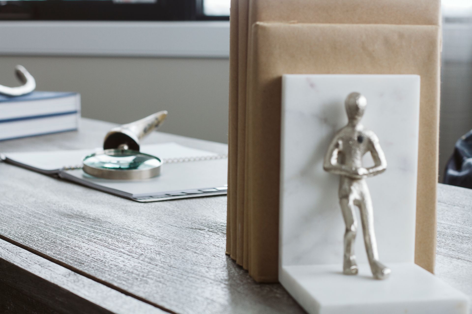 A bookend with a statue of a man on it is on a desk.