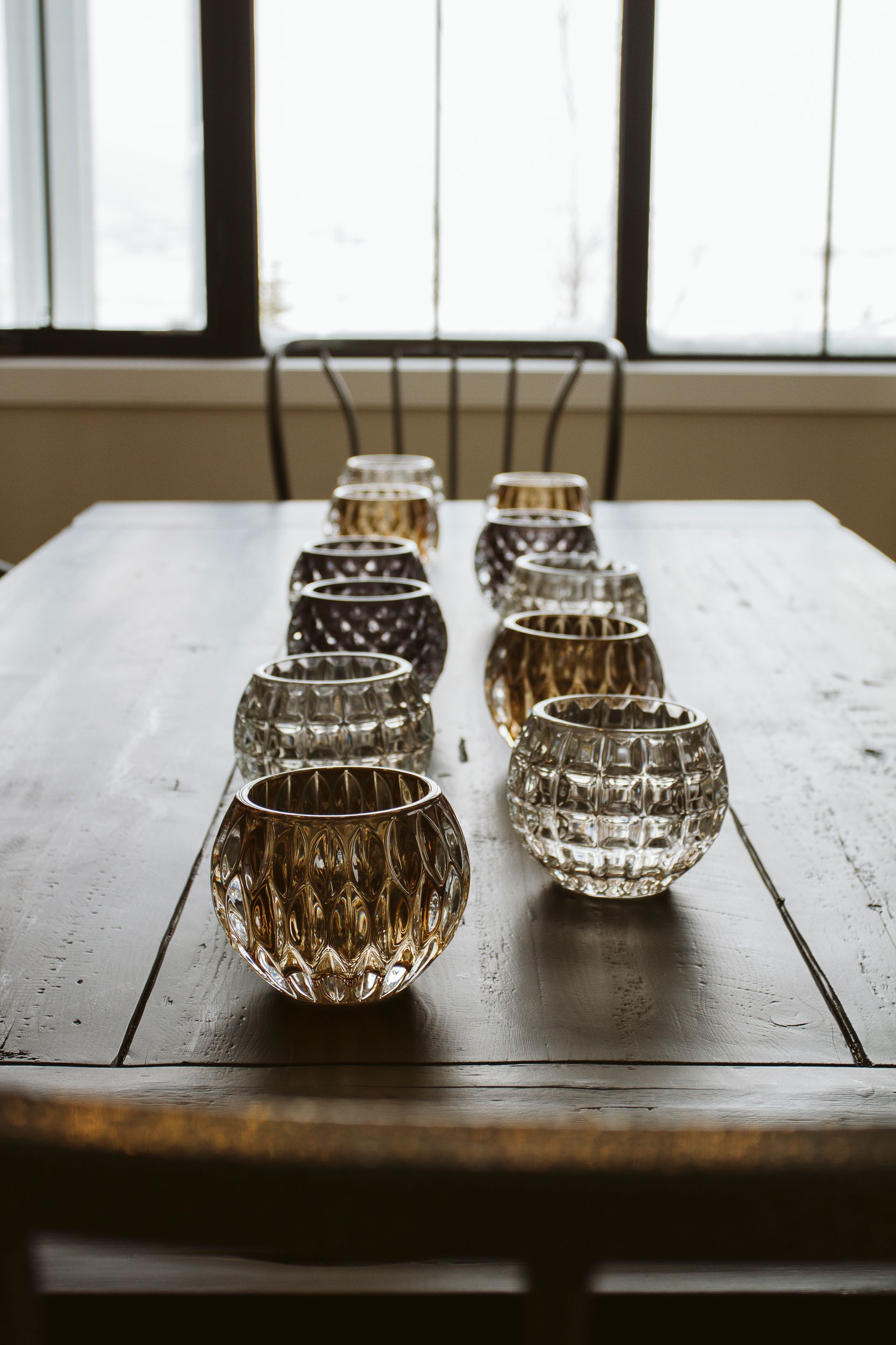 A row of candle holders are lined up on a wooden table.