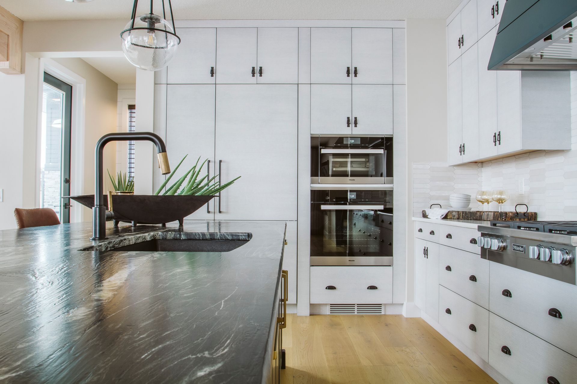 A kitchen with black counter tops , white cabinets , and stainless steel appliances.