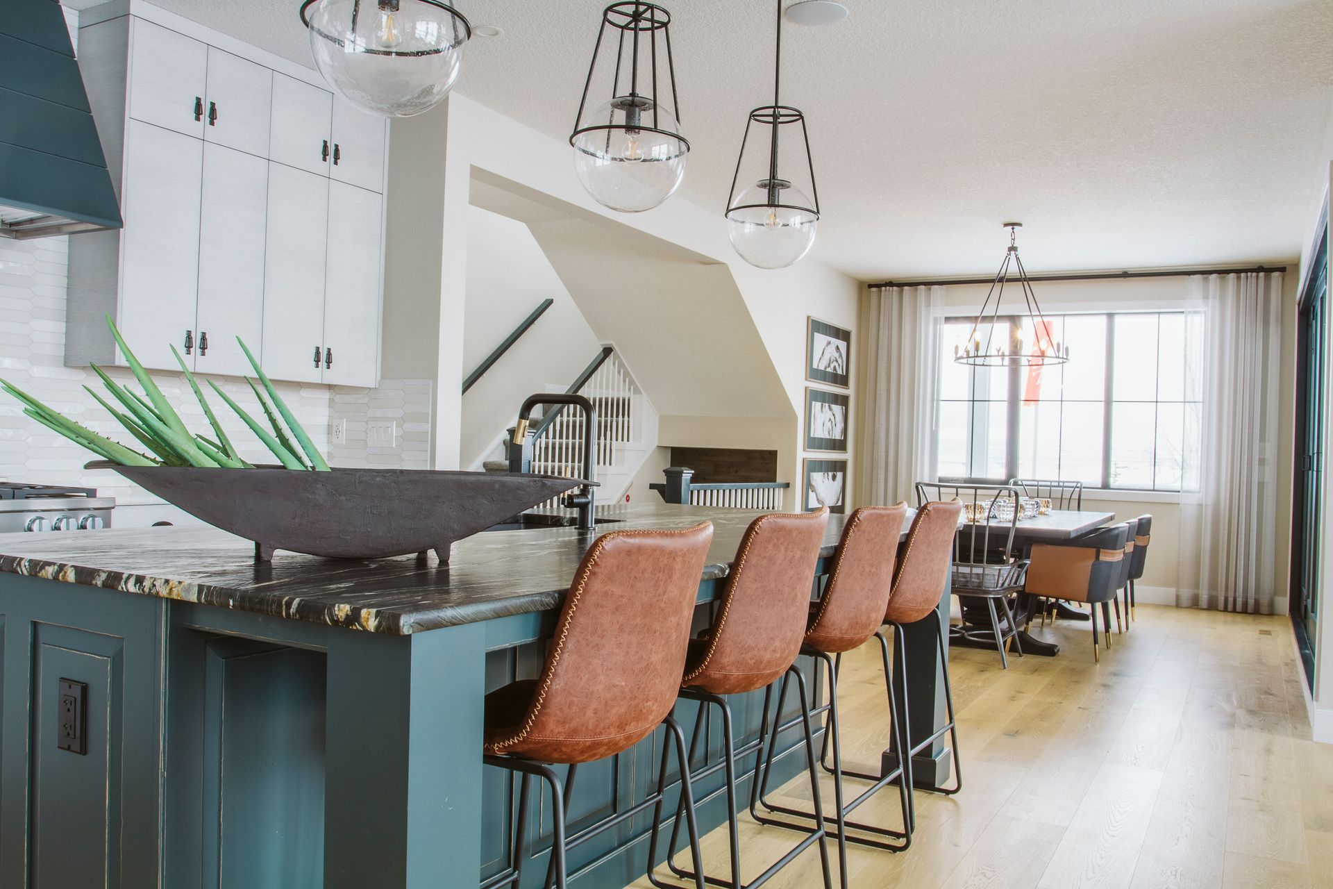 A kitchen with a bar and stools and a dining room in the background.