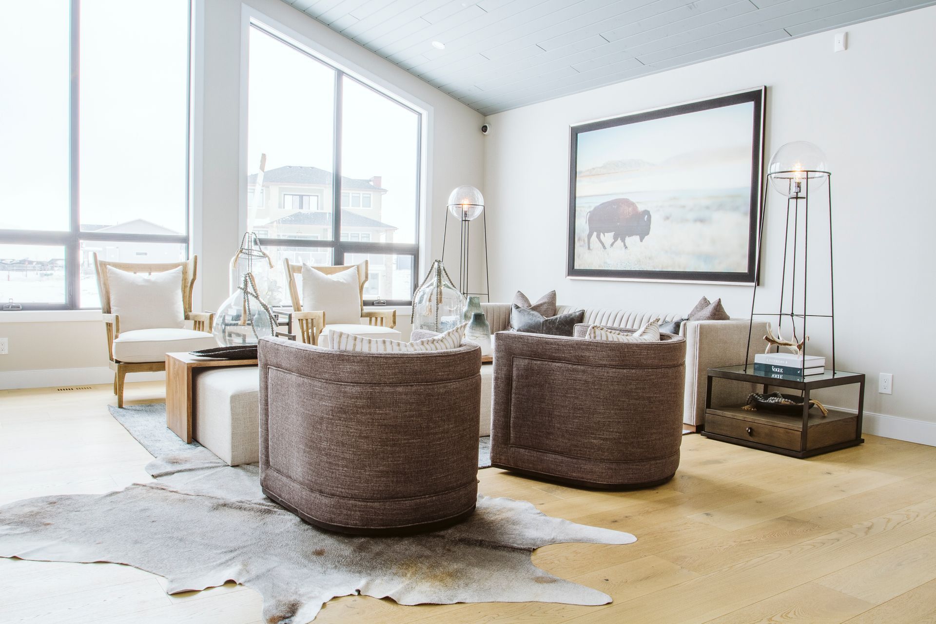 A living room with a couch , chairs , ottoman and a cowhide rug.