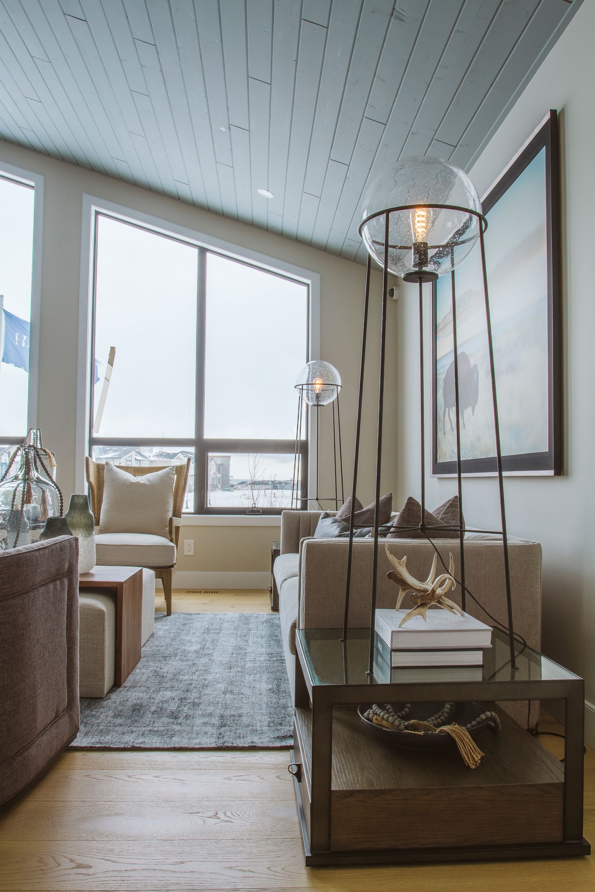 A living room with a couch , chair , table , and large windows.