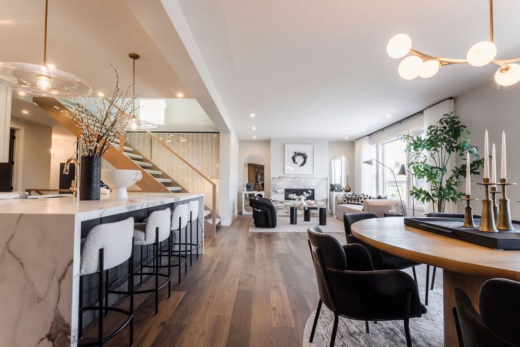 A large living room with a table and chairs and a staircase leading to the second floor.