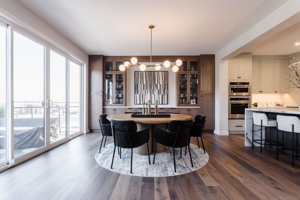 A dining room with a round table and chairs and a chandelier hanging from the ceiling.