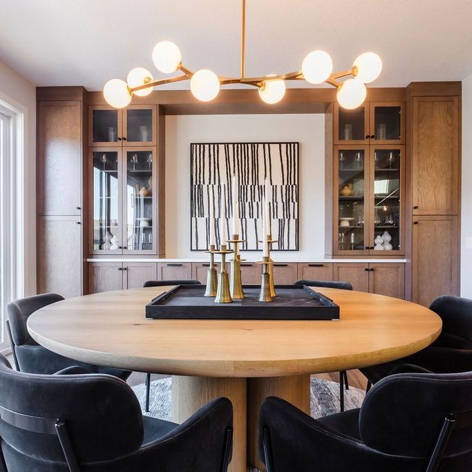 A dining room with a round wooden table and black chairs