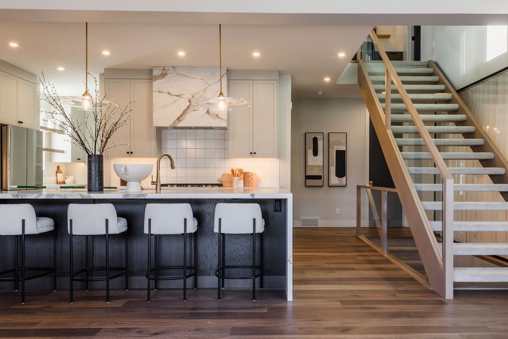 A kitchen with a large island and stairs leading up to the second floor.