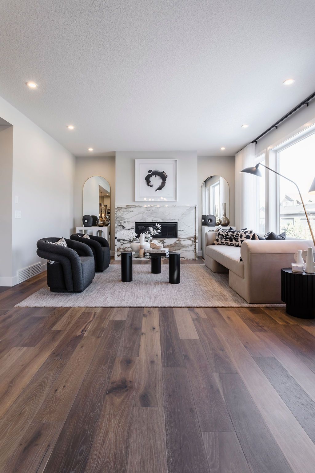 A living room with hardwood floors , a couch , chairs , and a fireplace.