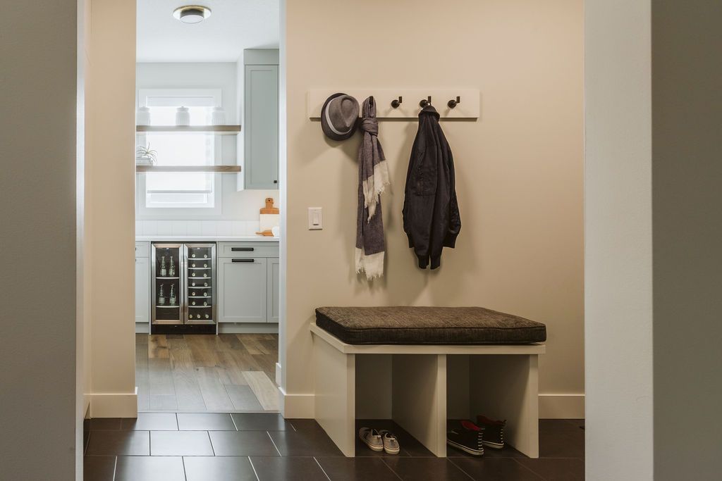 A hallway with a bench and hooks on the wall.