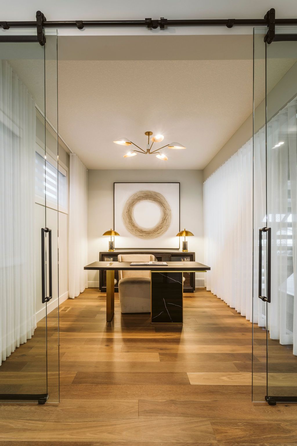 There is a desk in the middle of the room with sliding glass doors.