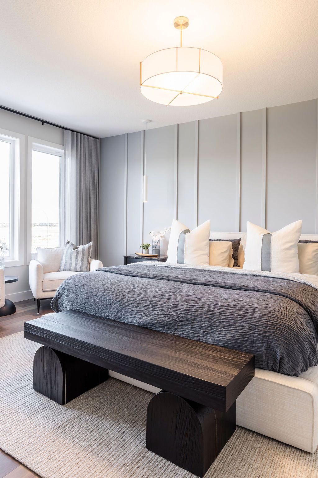 A bedroom with a king size bed , a bench , and a chandelier.