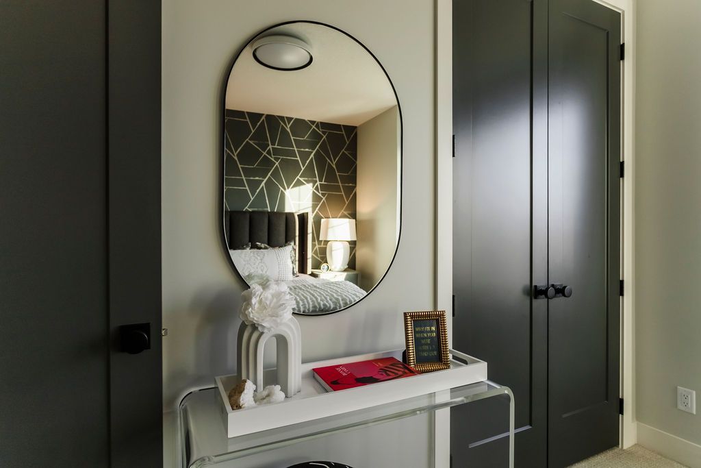 A bedroom with a round mirror on the wall and a table.