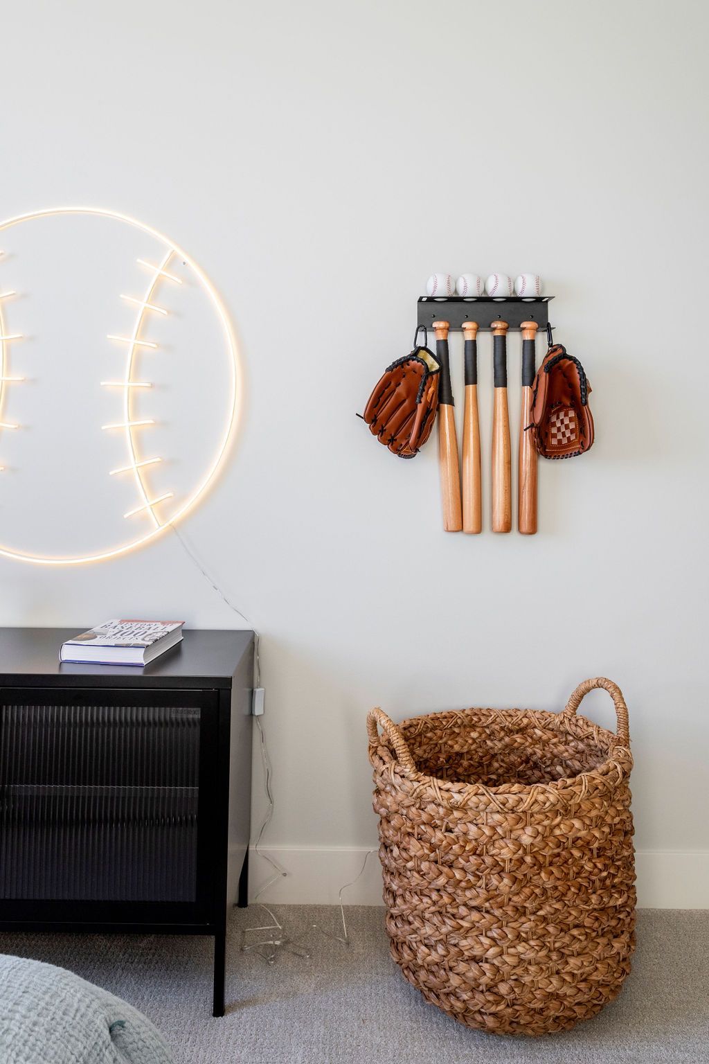 A baseball and gloves hanging on a wall next to a basket.