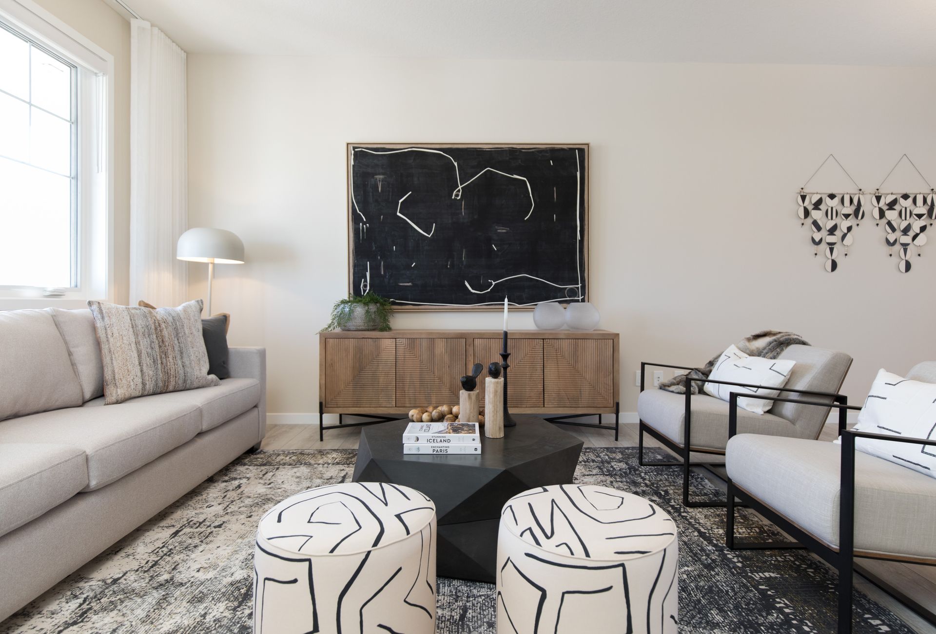 A living room with a couch , chairs , ottomans and a television.
