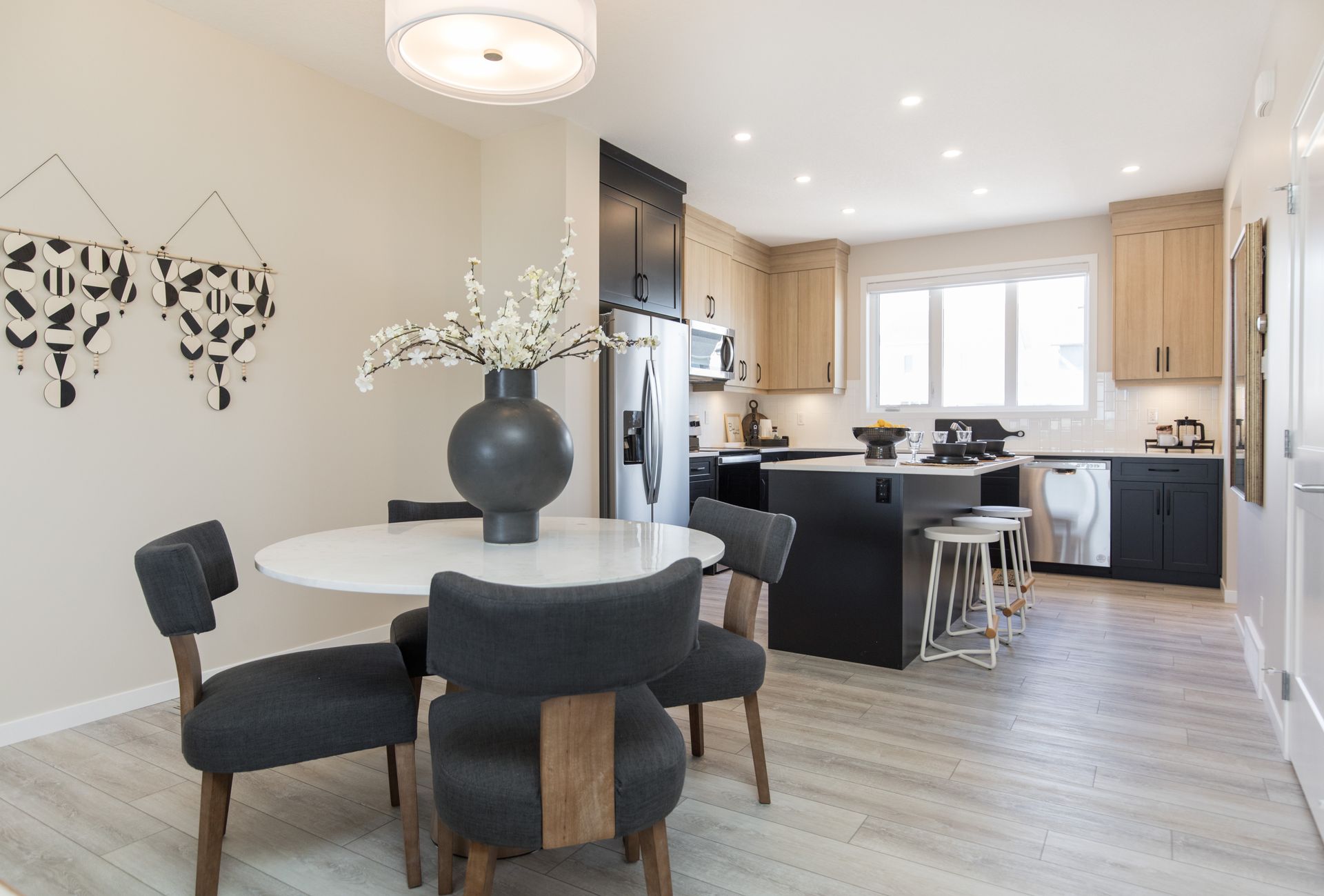 A dining room with a table and chairs and a kitchen in the background.