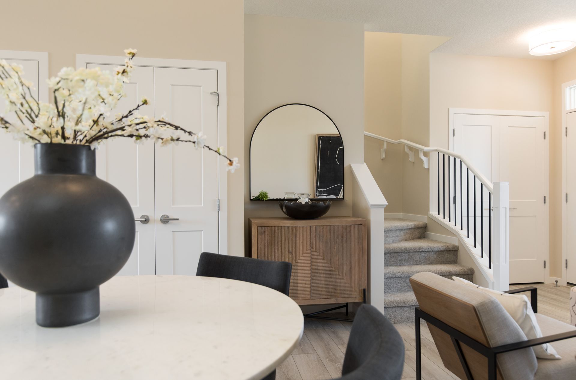 A living room with a table and chairs and a vase of flowers on the table.