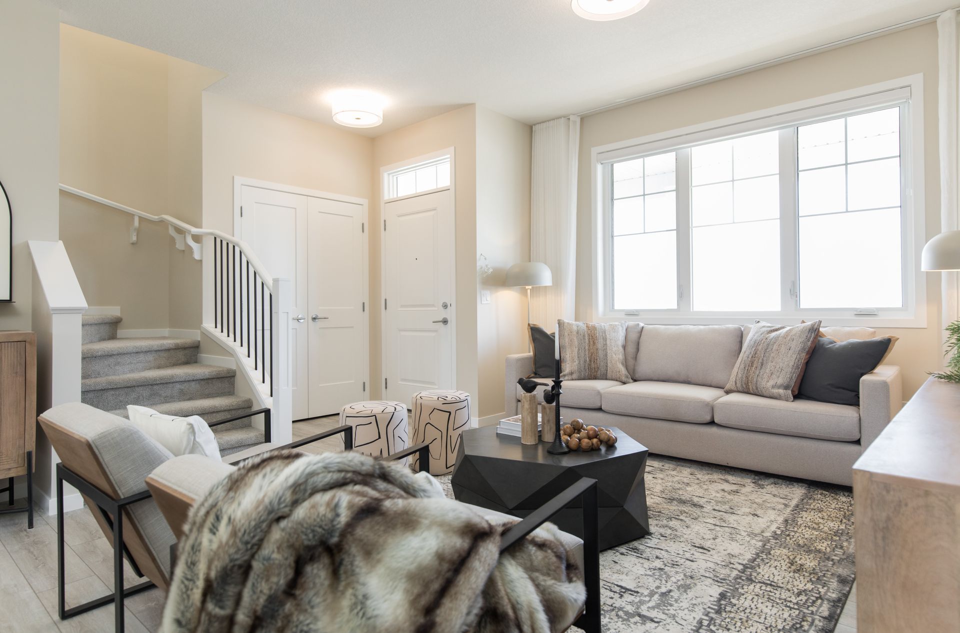 A living room with a couch , chair , coffee table and stairs.