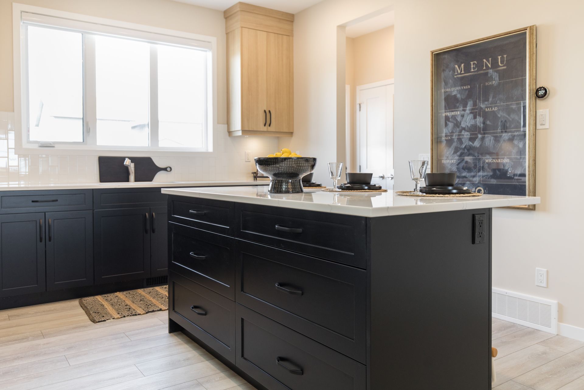 A kitchen with black cabinets and a large island in the middle.