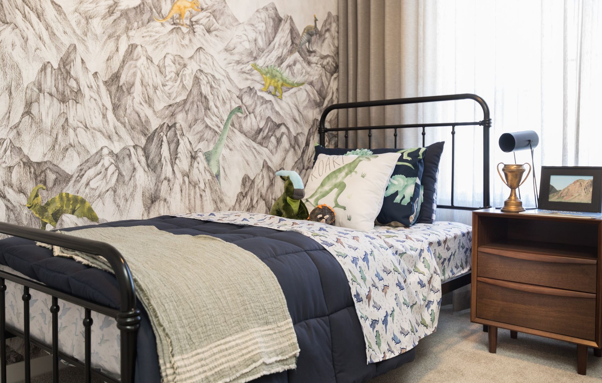 A bedroom with a bed , nightstand , and mountains on the wall.