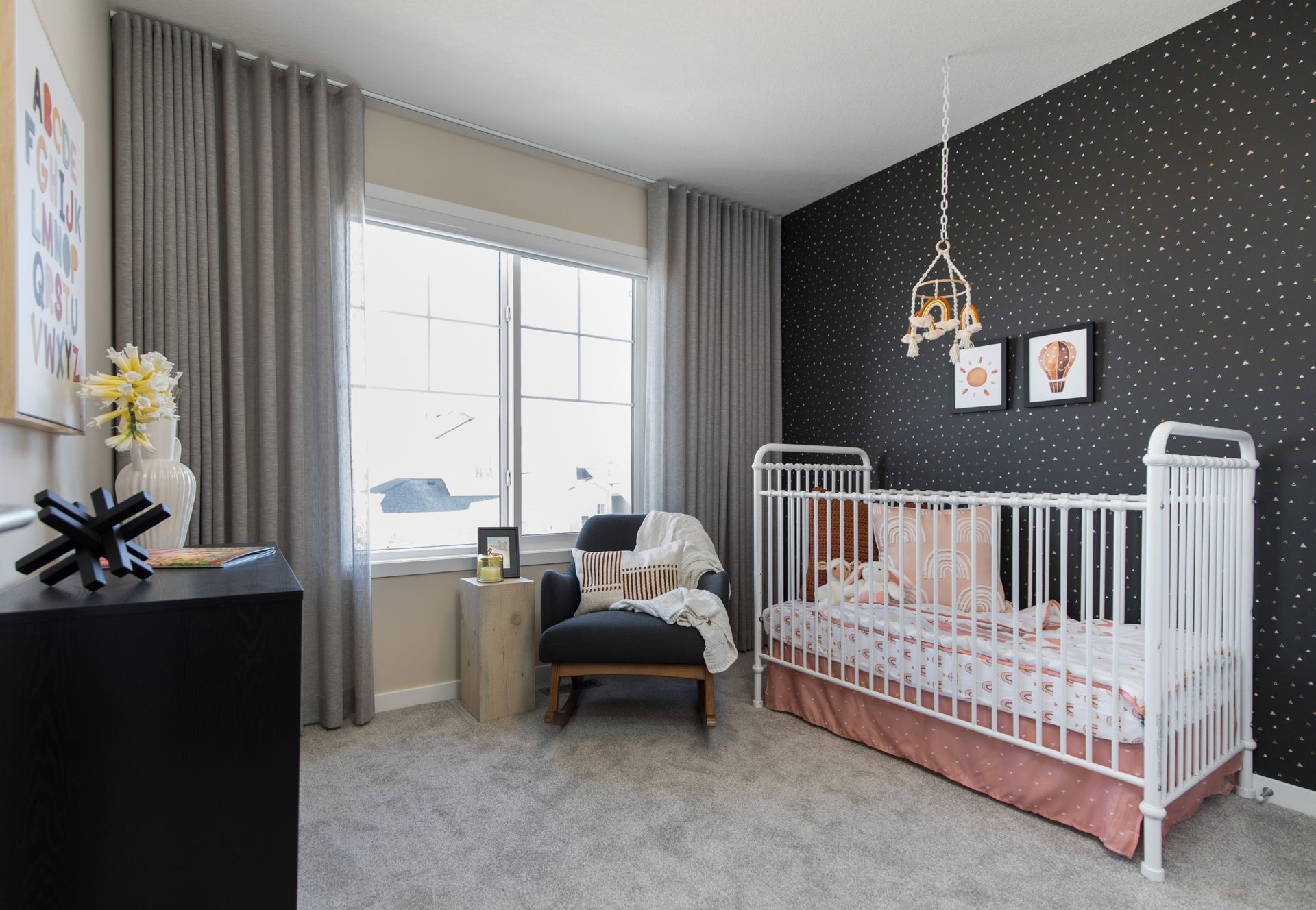 A nursery with a crib , chair , and window.