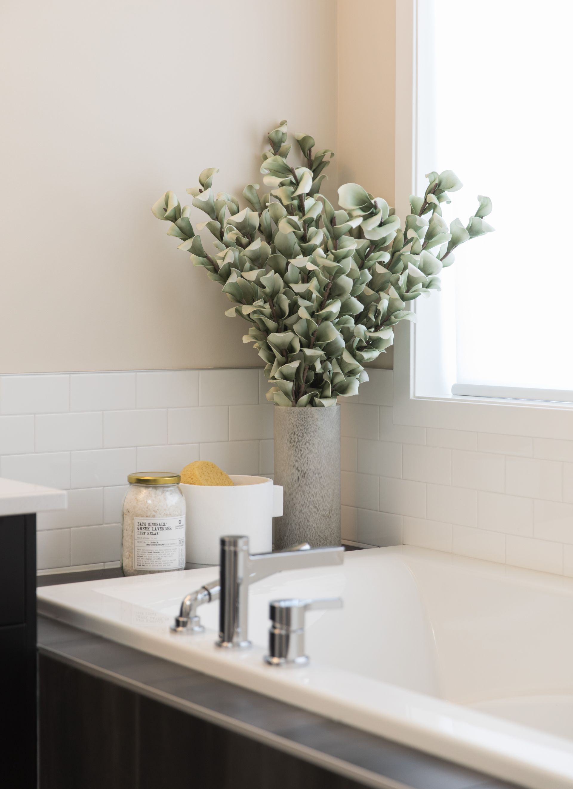 A bathroom with a bathtub and a vase of flowers on the counter.