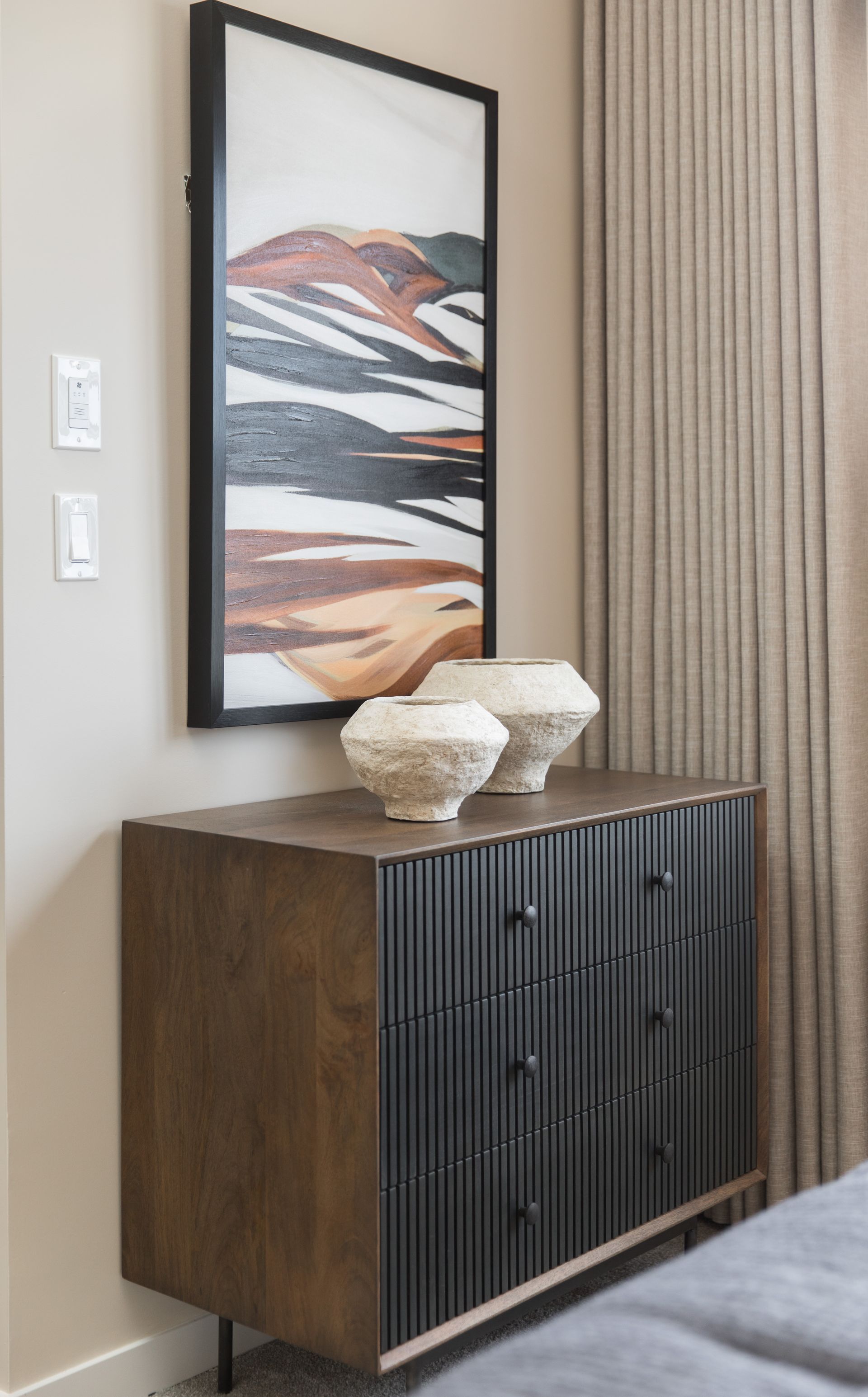 A bedroom with a dresser , vases and a painting on the wall.