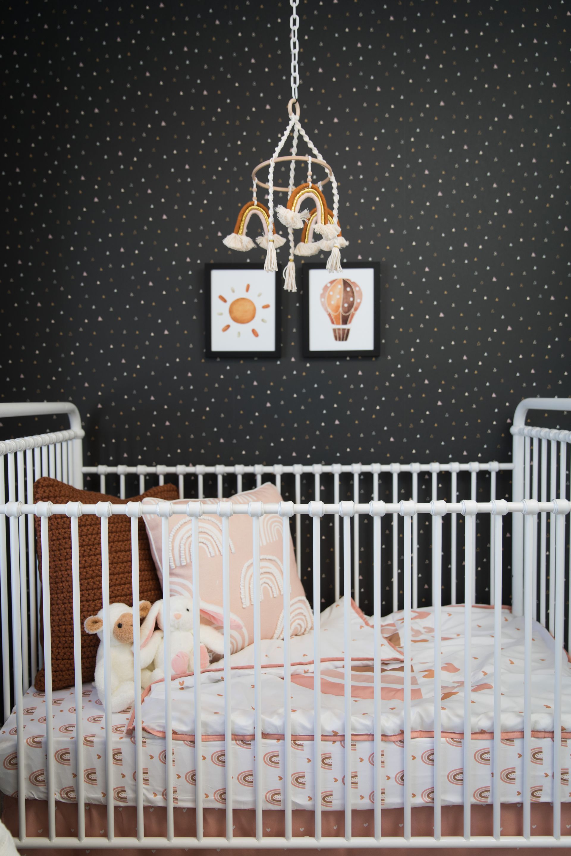A baby crib with a mobile hanging from the ceiling in a nursery.