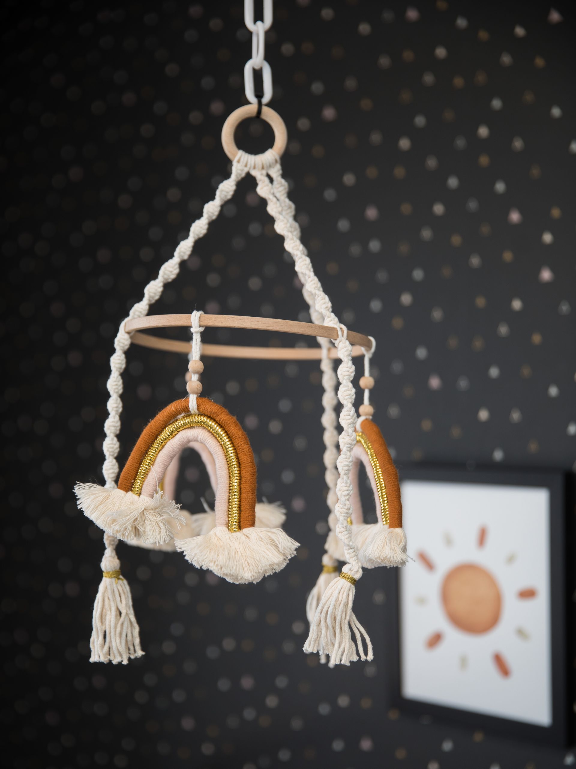 A baby mobile with rainbows and tassels hanging from the ceiling