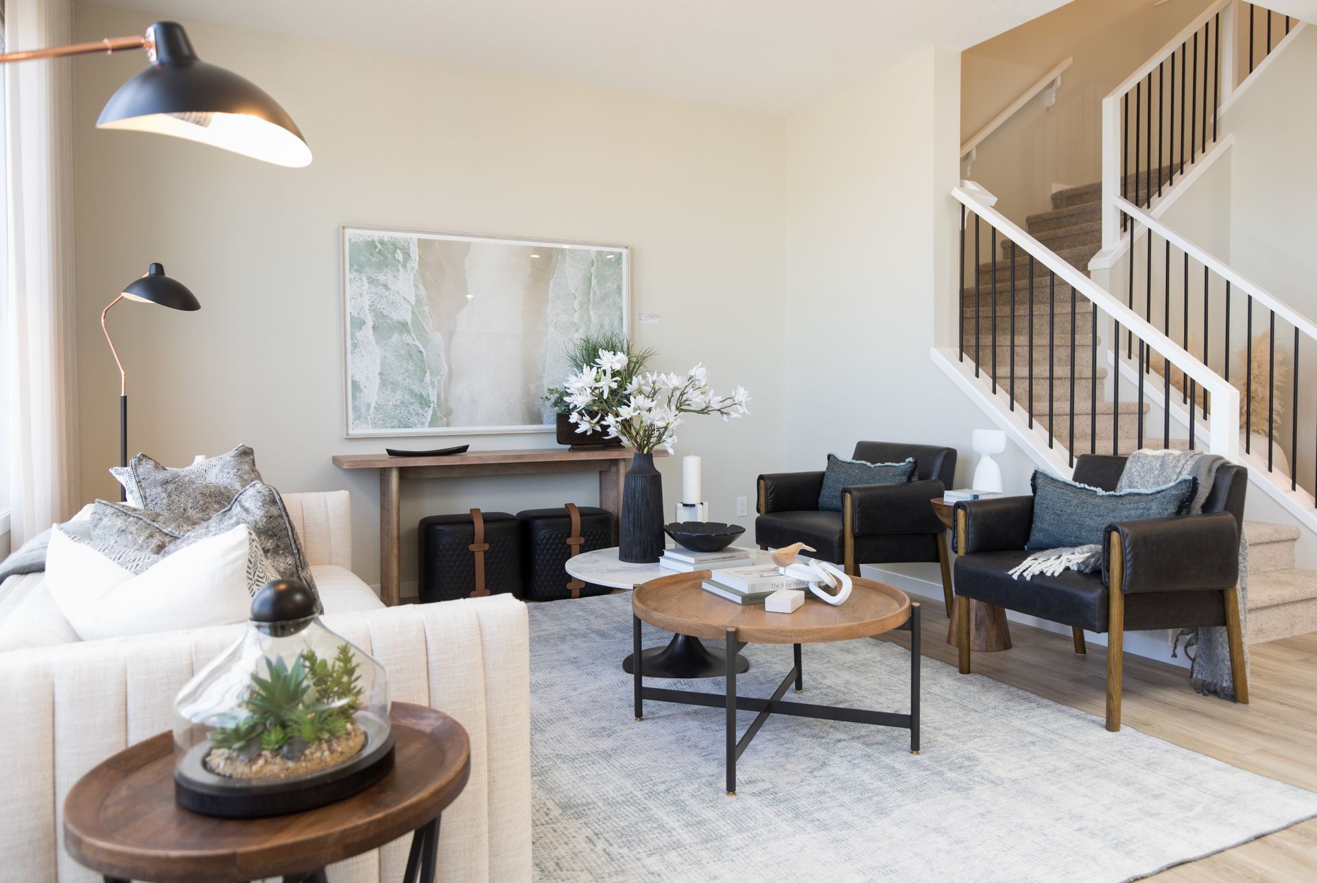 A living room with a couch , chairs , coffee table and stairs.