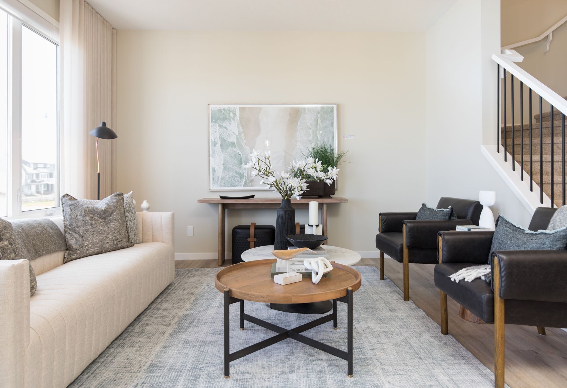 A living room with a couch , chairs , coffee table and stairs.