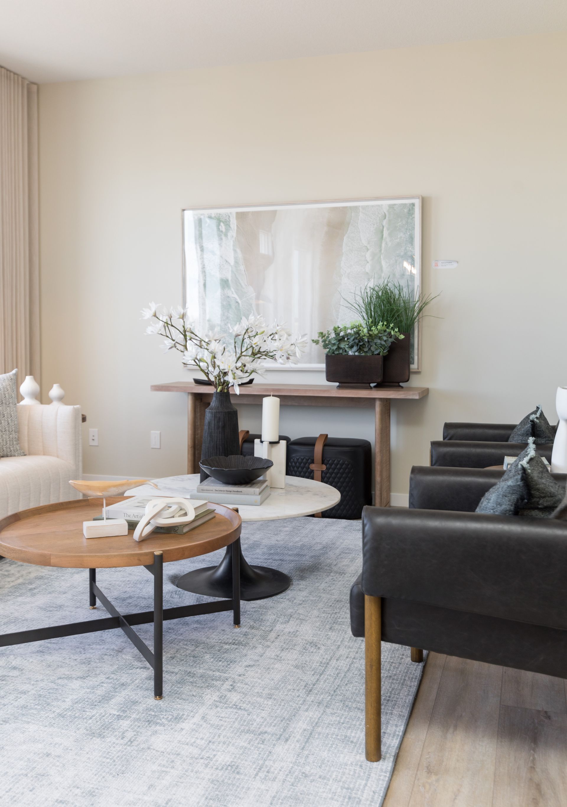 A living room with a couch , chair , coffee table and mirror.