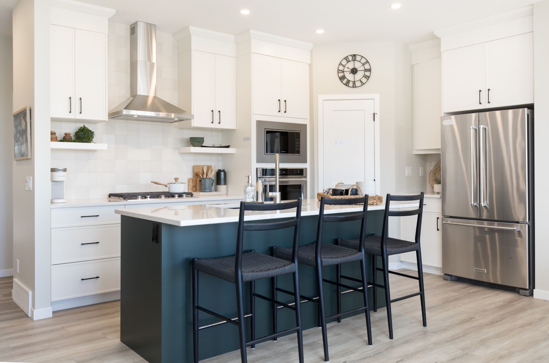 A kitchen with white cabinets , stainless steel appliances , and a large island.