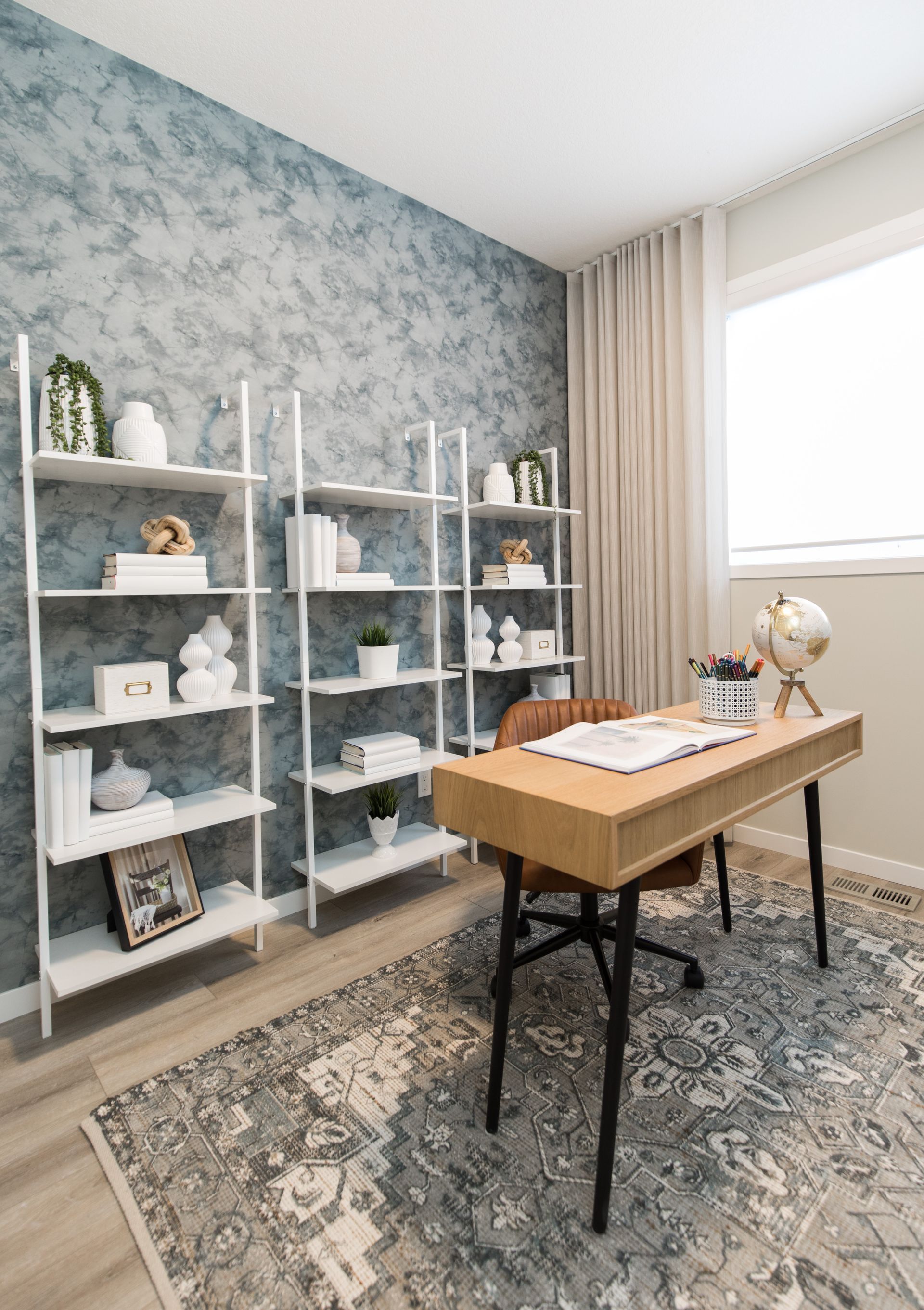 A home office with a desk , chair , shelves and a rug.