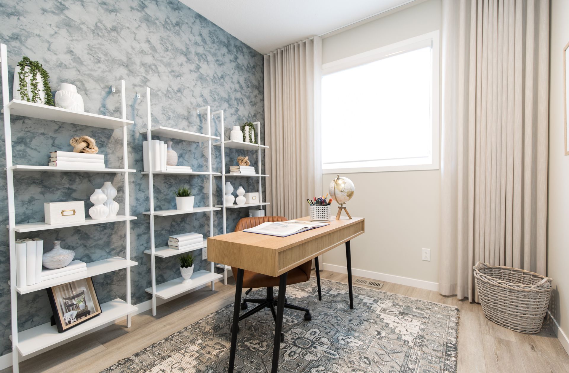 A home office with a desk , chair , shelves and a window.