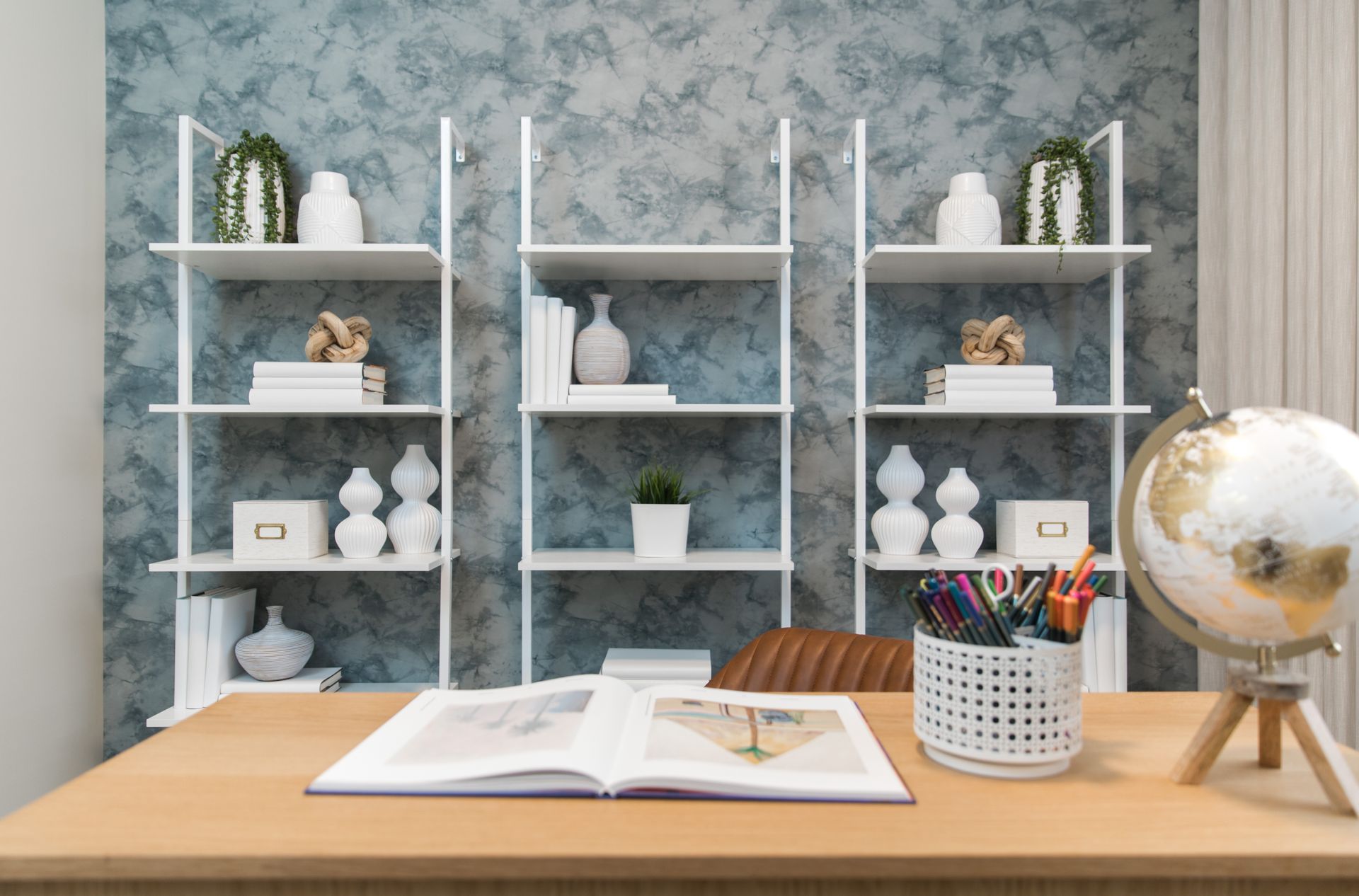 A home office with a desk , shelves and a globe.