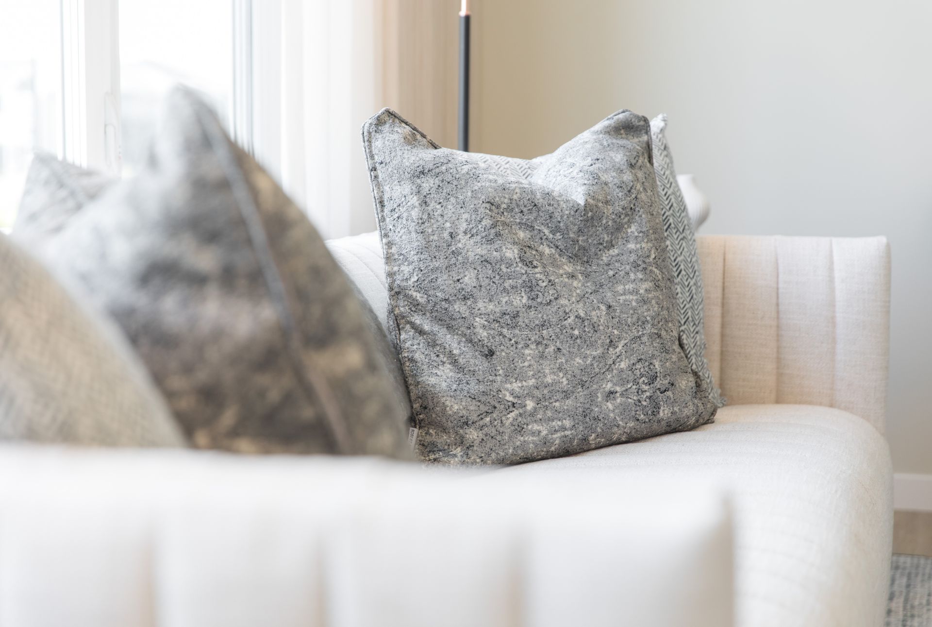 A white couch with gray pillows on it in a living room.