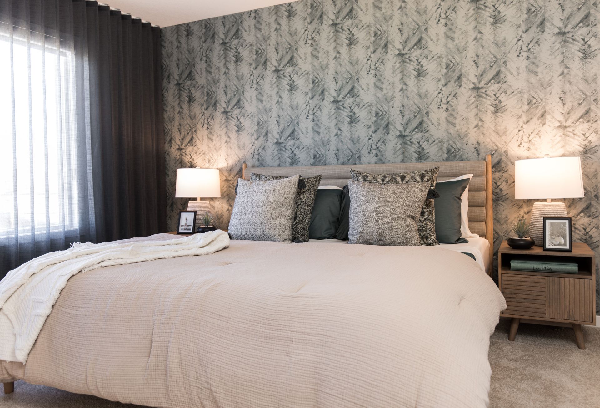 A bedroom with a bed , nightstand , lamps and a window.