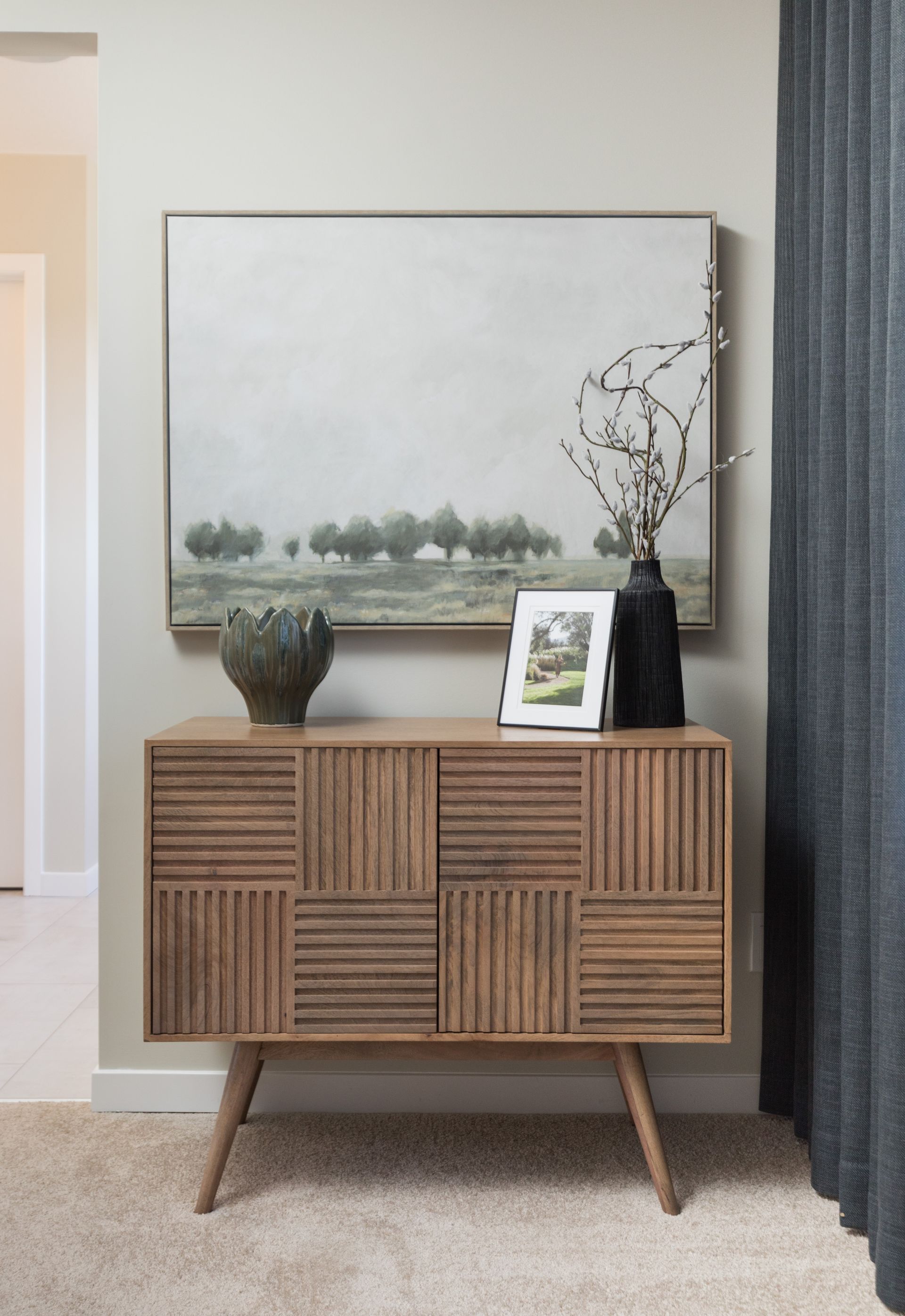 A wooden dresser with a painting on the wall above it