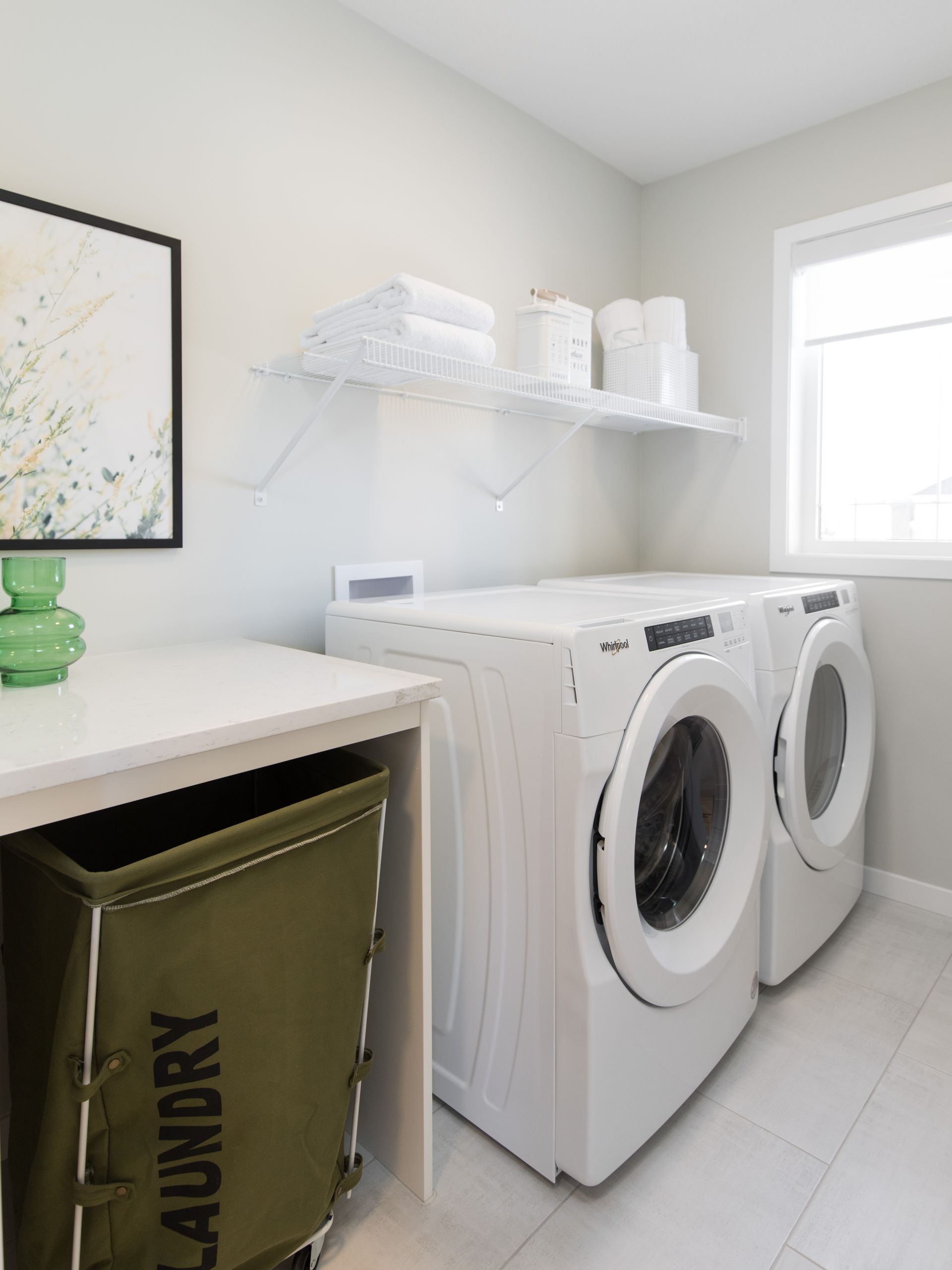 A laundry room with two washing machines and a green laundry bag