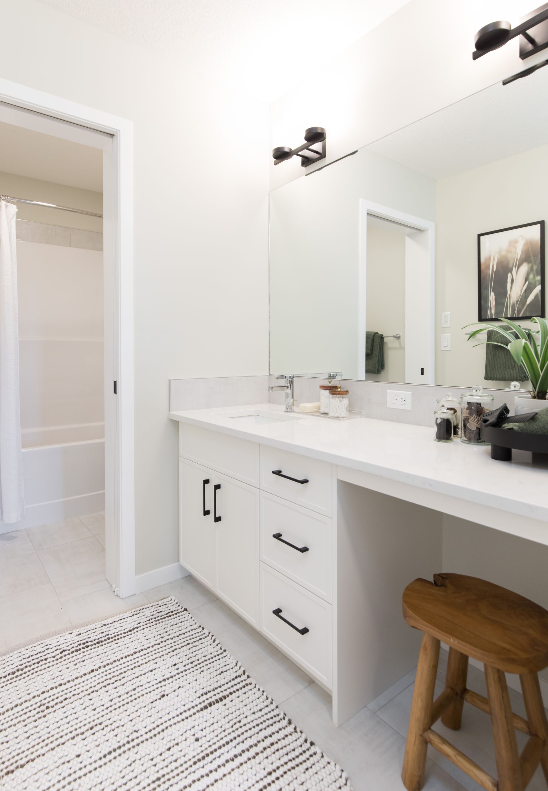 A bathroom with a vanity , sink , mirror and stool.