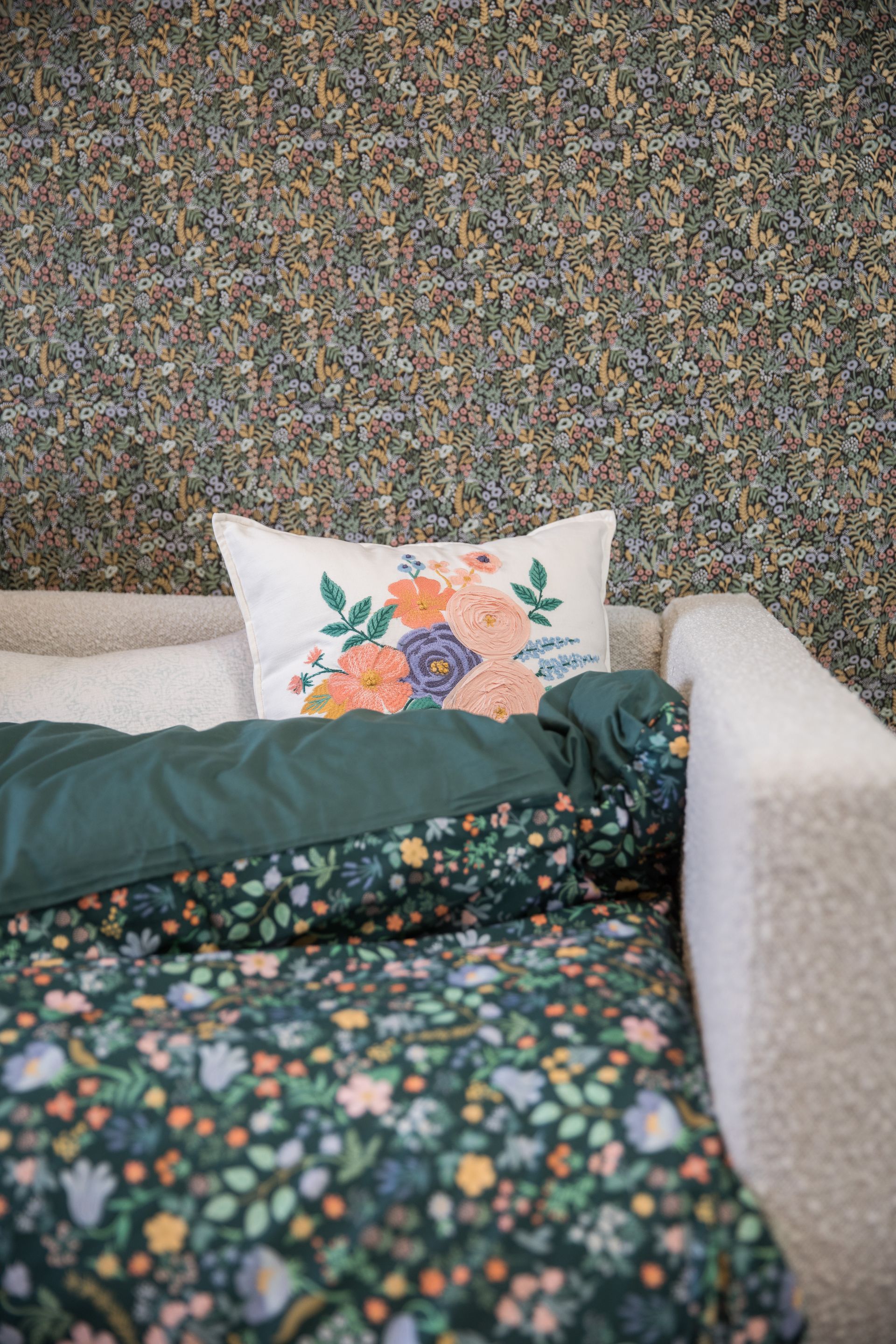 A couch with a floral comforter and a pillow on it.
