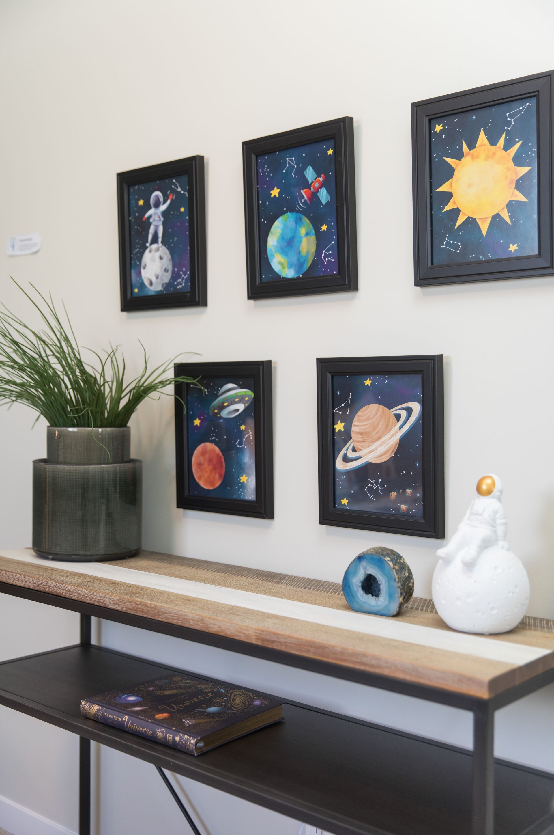 A table with a plant on it and a bunch of pictures on the wall.