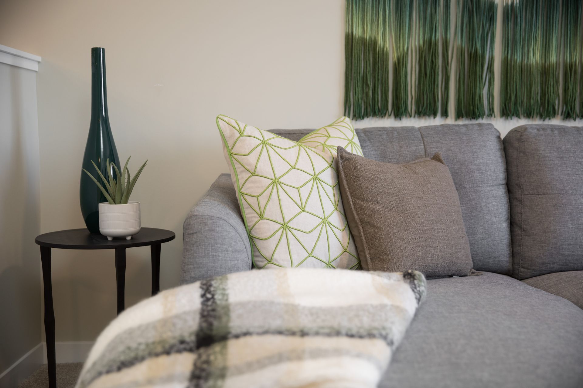 A living room with a couch , table , vase and pillows.